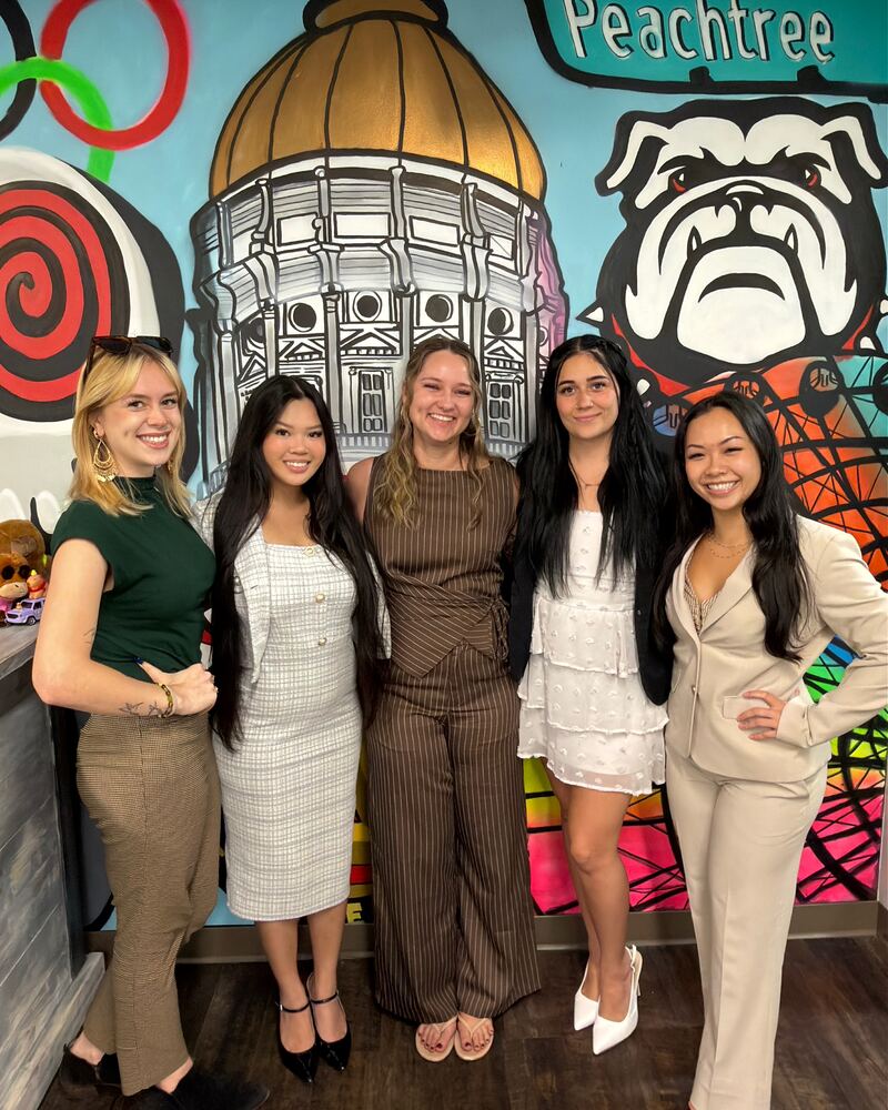 Five Iron Peak Collective team members in front of a colorful mural