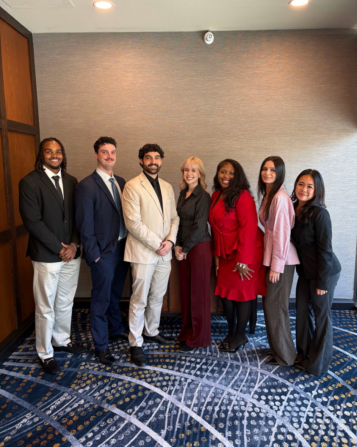 Seven Iron Peak Collective team members in business attire standing together in a hotel meeting room